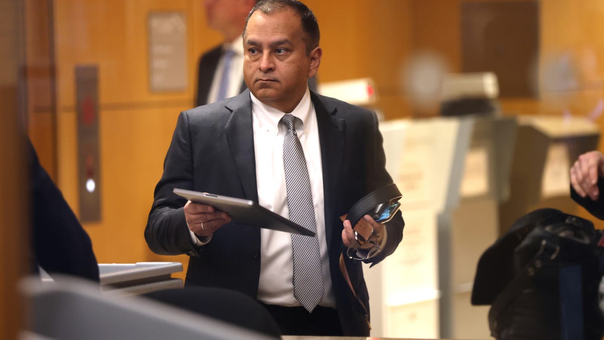 Ramesh Balwani in a courthouse holding his tablet and personal items in his hands