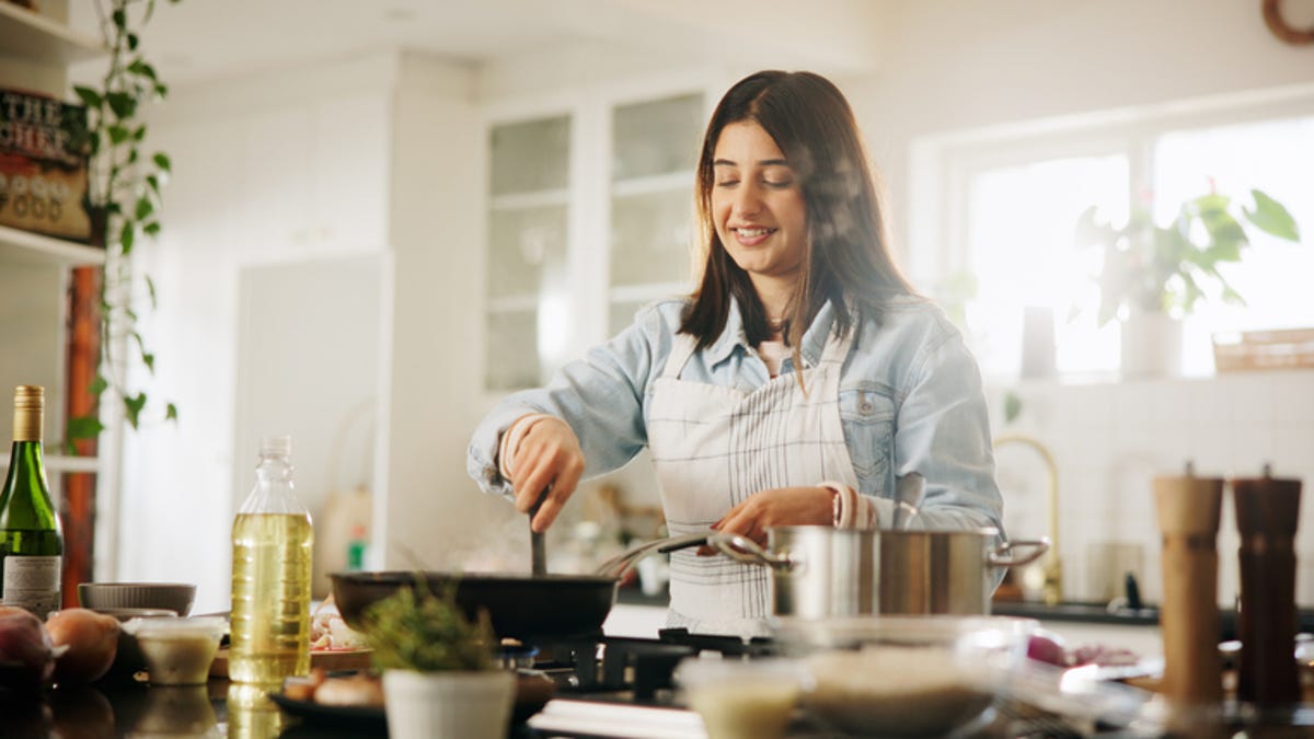 Woman meal prepping different meals and placing them in glass storage containers