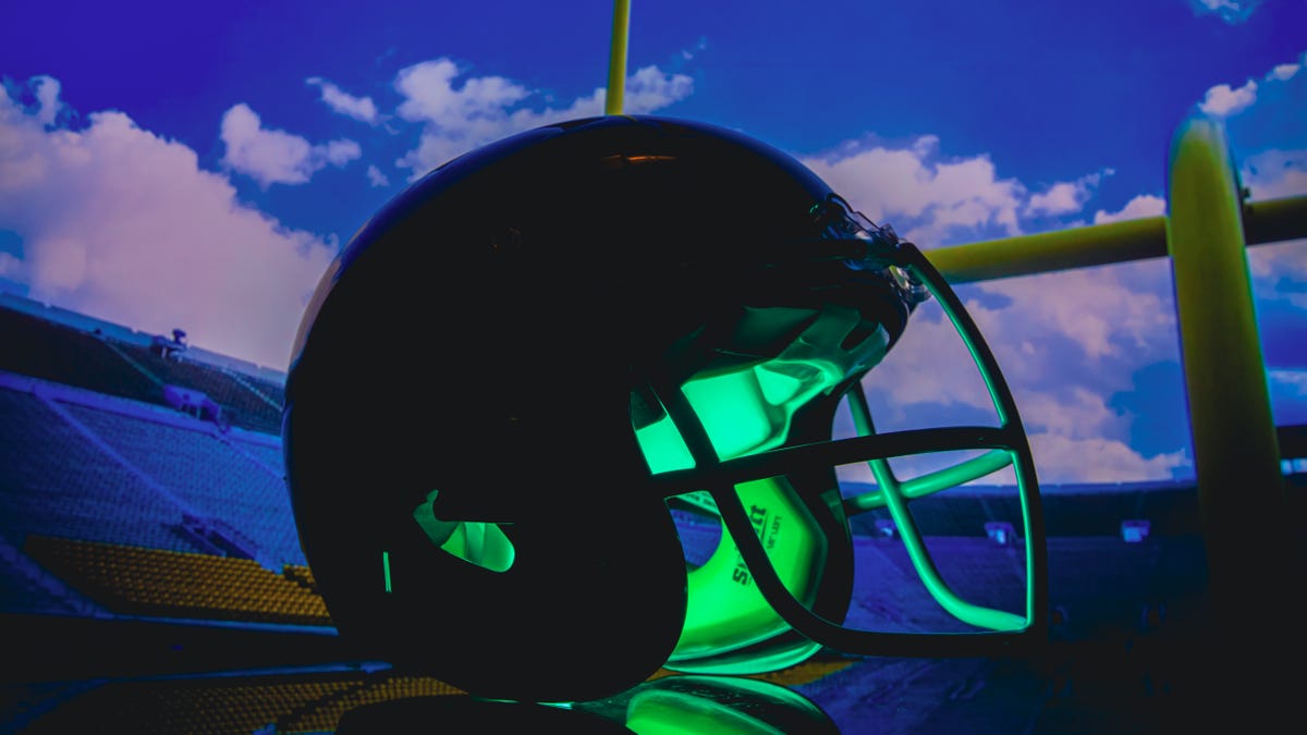 illuminated football helmet with field in the backdrop