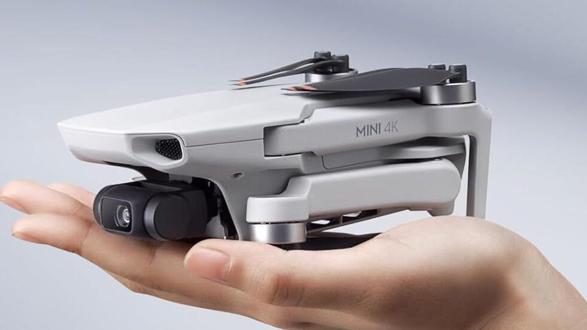 A DJI drone sits in the palm of a hand.