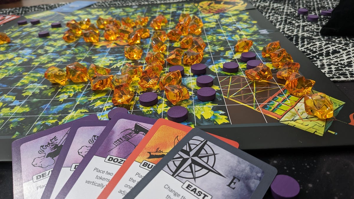 A hand of cards laid down on a game board with orange crystals and purple counters