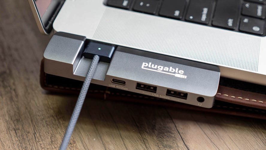 Plugable 5-in-1 USB C Hub with MagSafe support connected to a 16-inch MacBook Pro's USB-C ports on the left side of the laptop.