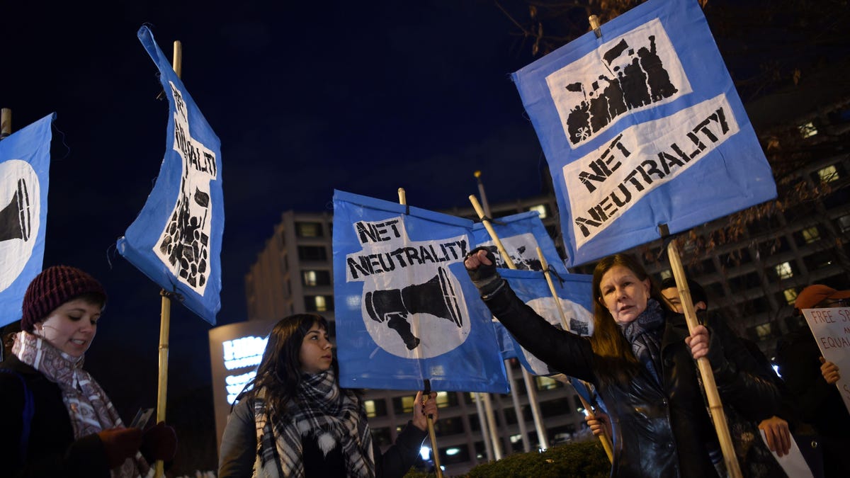 People at a protest hold signs in support of net neutrality