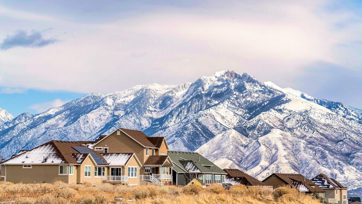 Houses with solar panels in front of snow covered mountains.