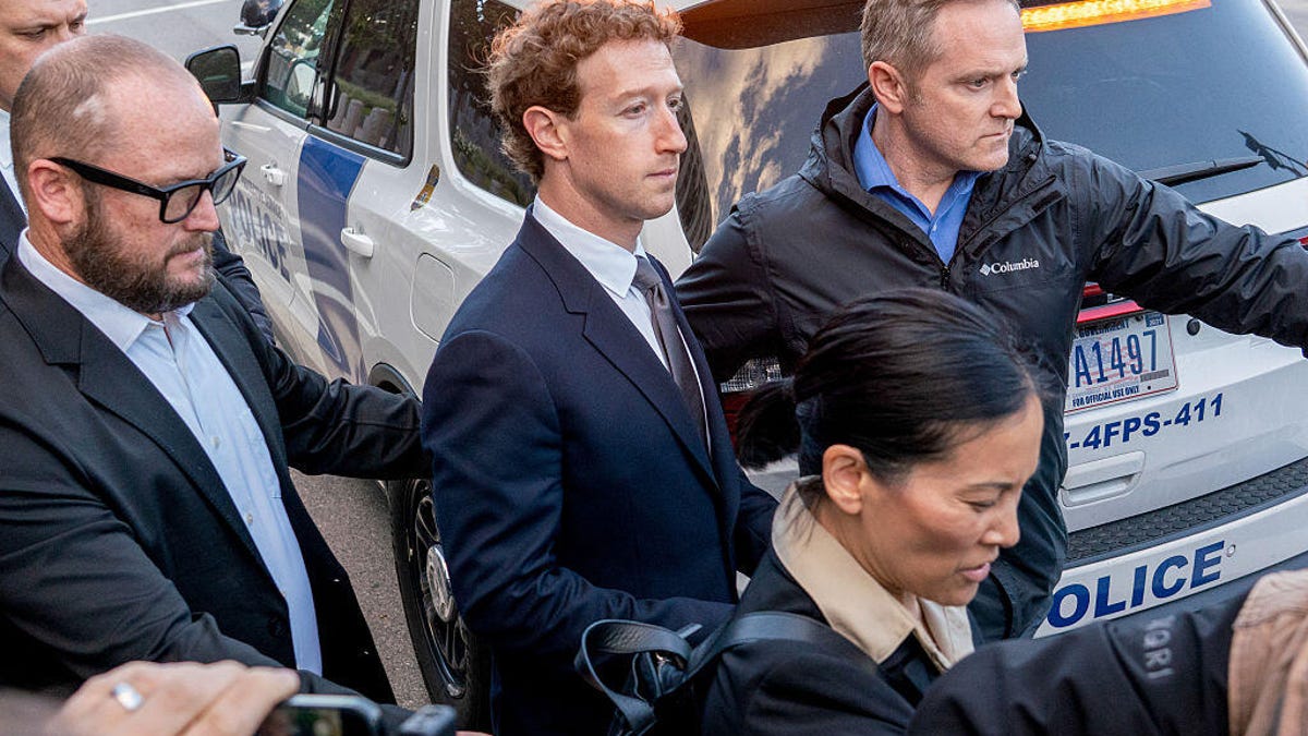 Mark Zuckerberg exits a courthouse surrounded by people in suits.
