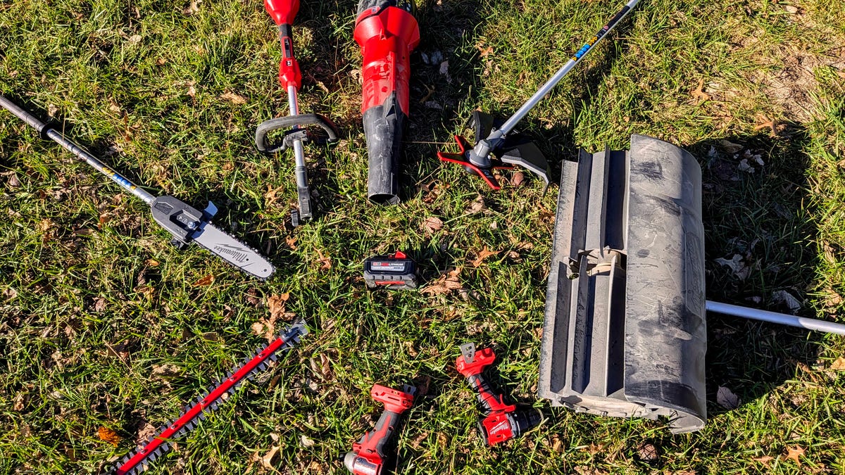 Eight different Milwaukee tools around a single battery in the grass.