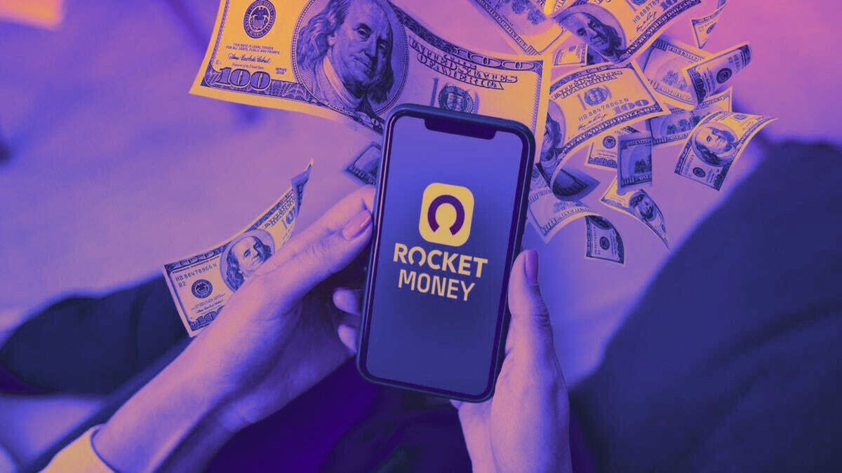 Holding a iphone with Rocket Money App on screen, money spreading out