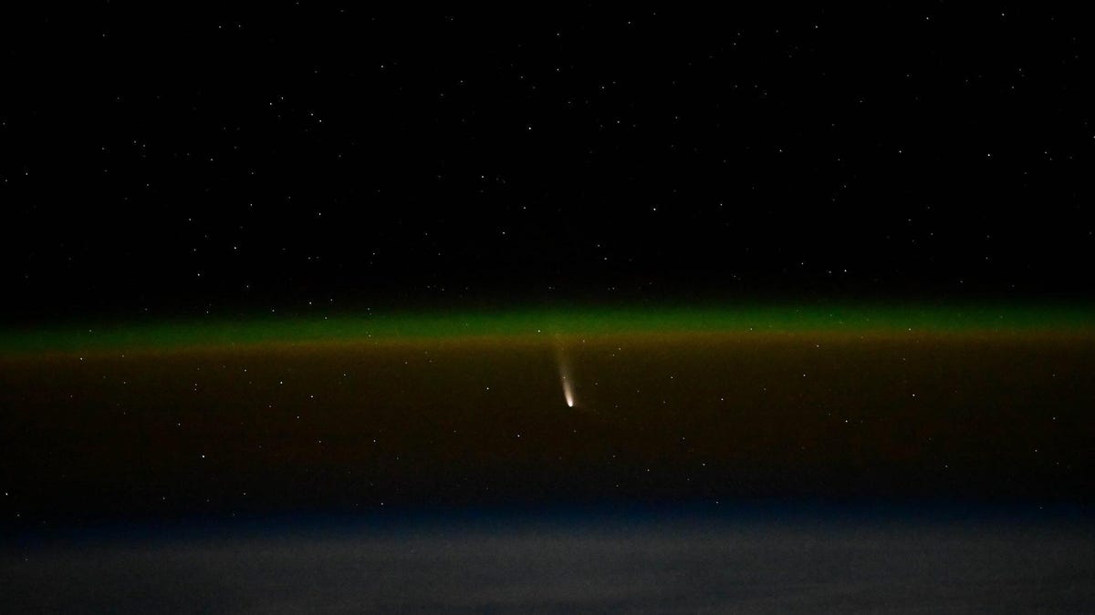 Green curve of Earth's atmosphere with bright splash of Comet A3 in the center.