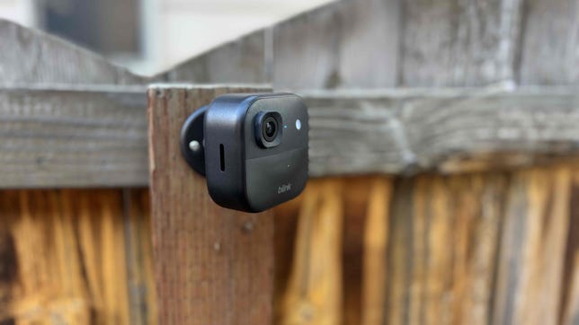 A Blink Outdoor 2K camera mounted to a wood fence.