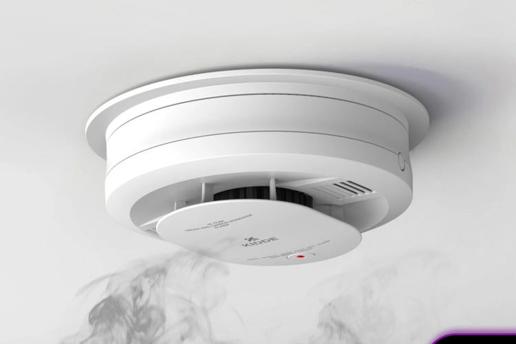 A white Kidde smoke detector on a white ceiling. 