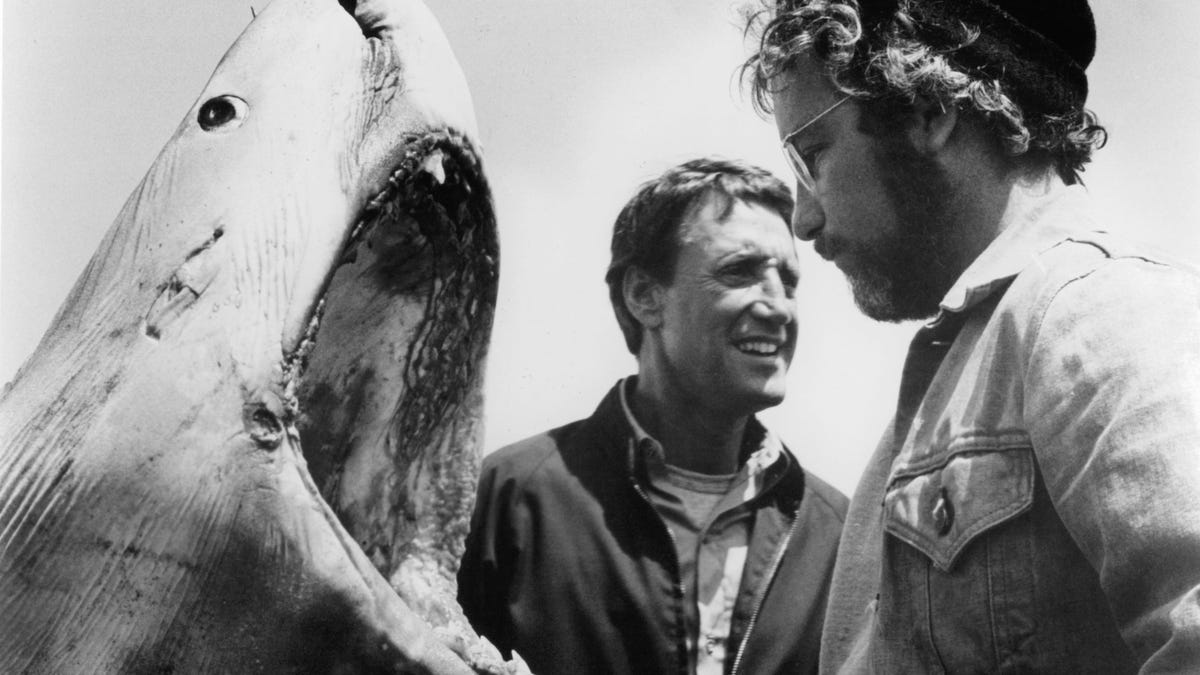 Actors Roy Scheider and Richard Dreyfuss stand next to a great white shark with a hook through its snout