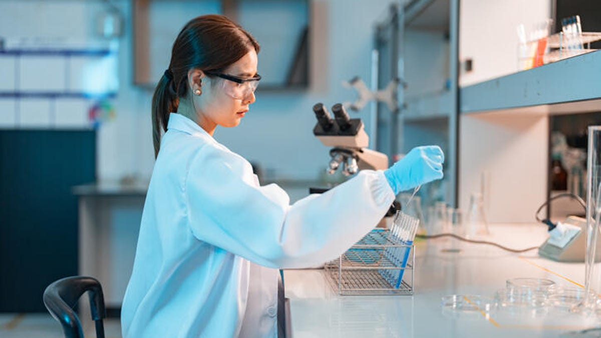 female scientist dressed in a lab coat and goggles working on a science project in a lab