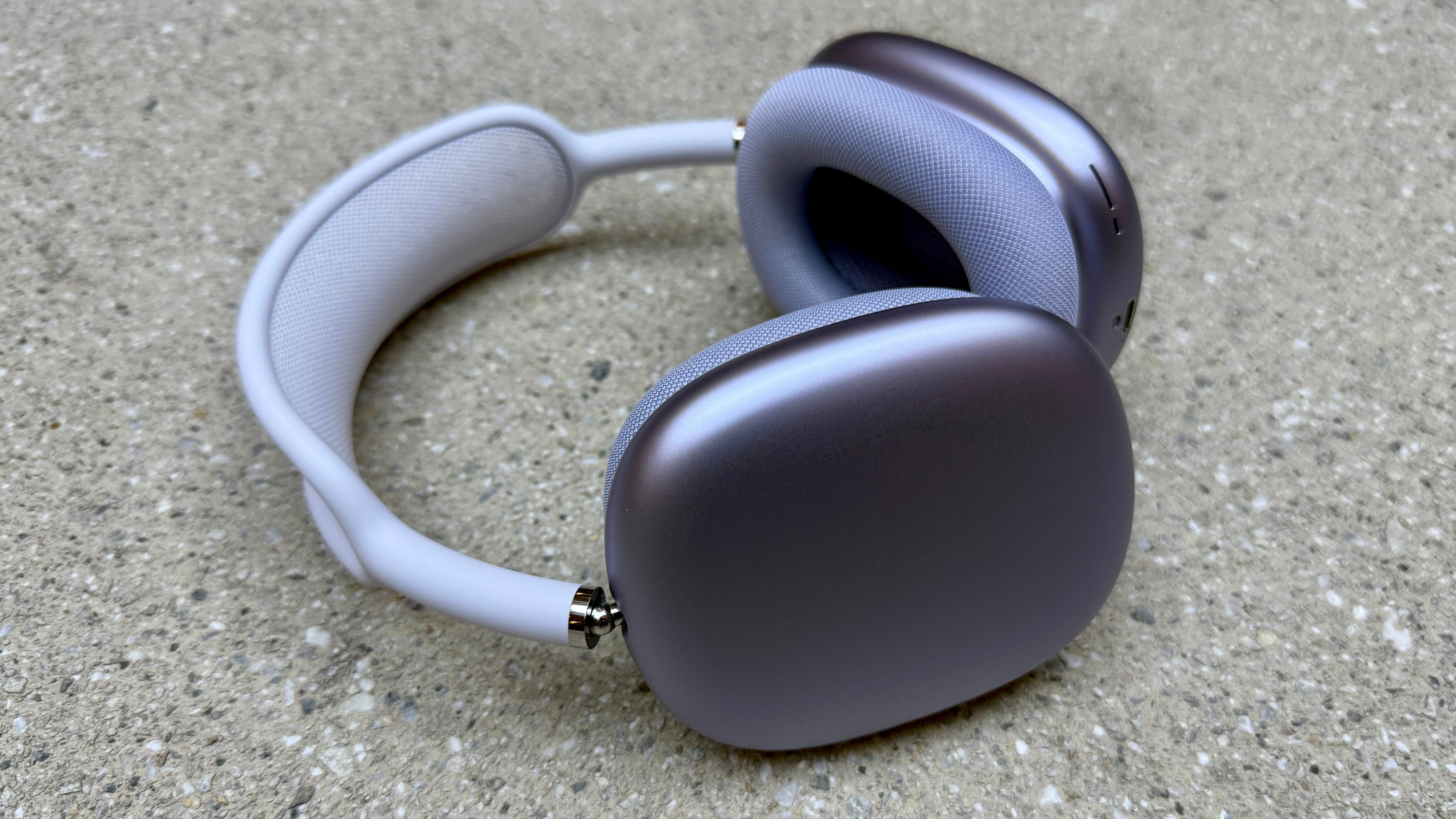 The purple version of the AirPods Max 2 laying on their side on a slate surface