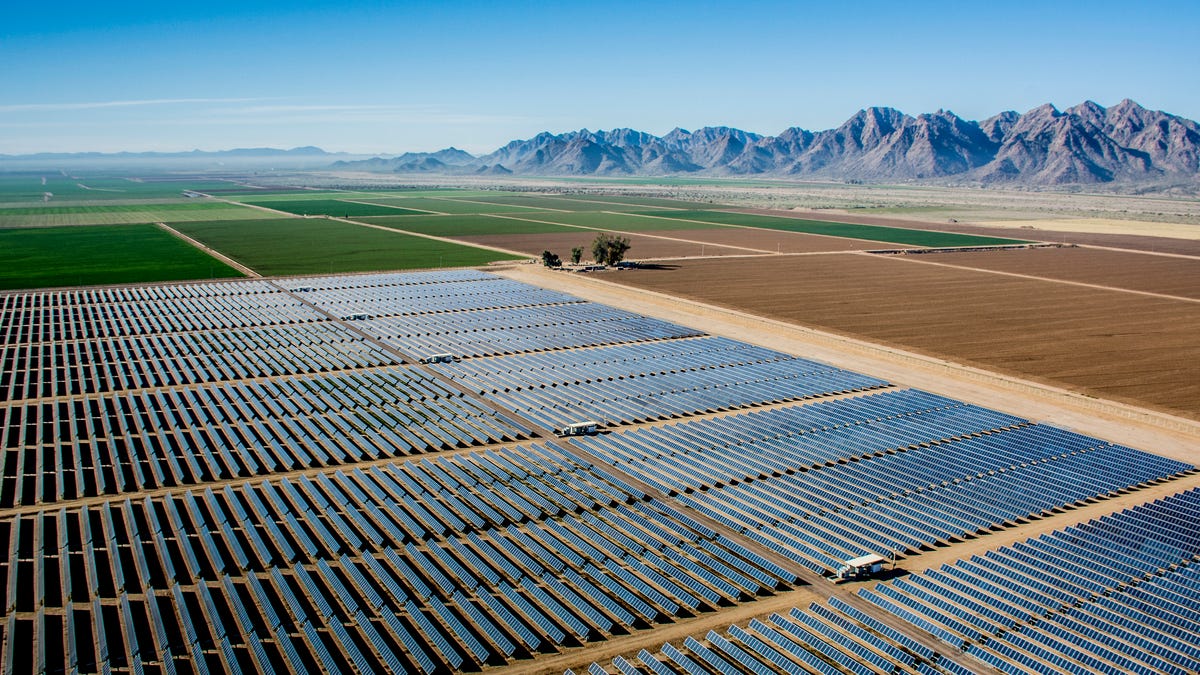 A solar farm in Arizona, with farmland and mountains in the background.
