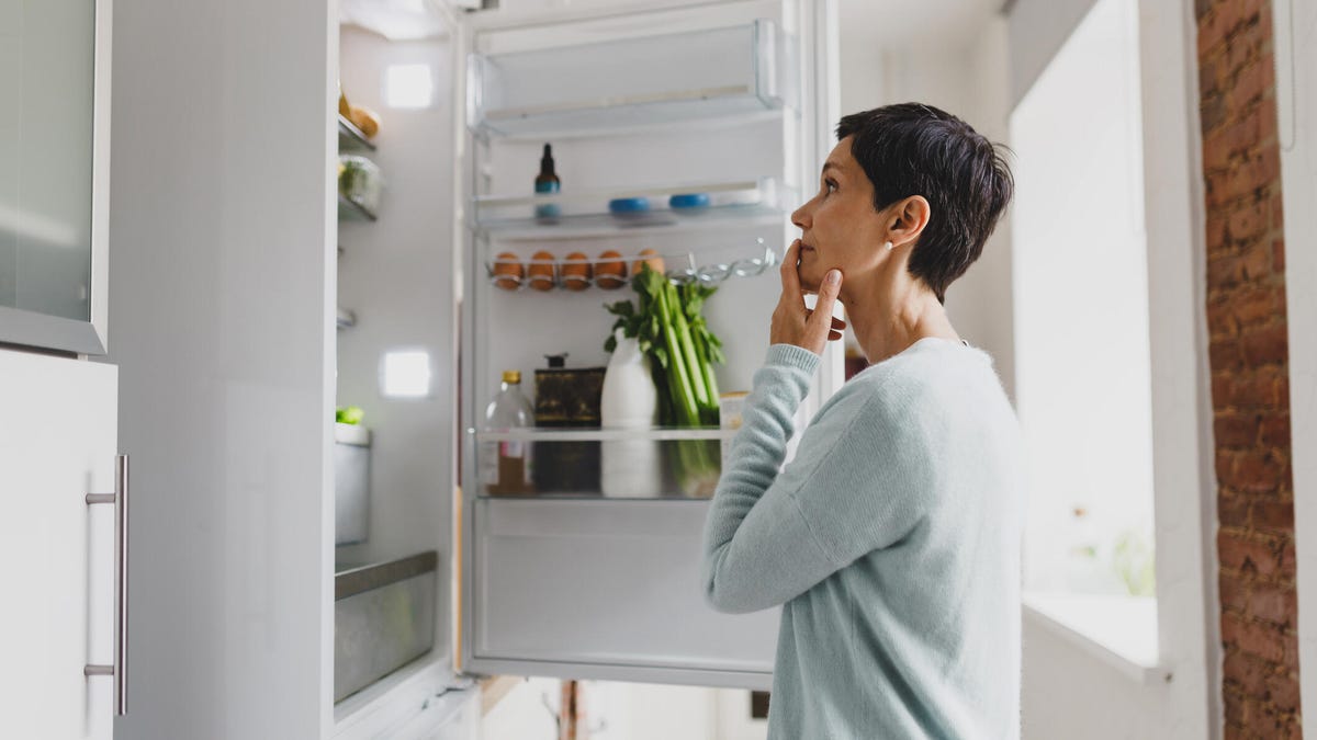 women looking into open fridge