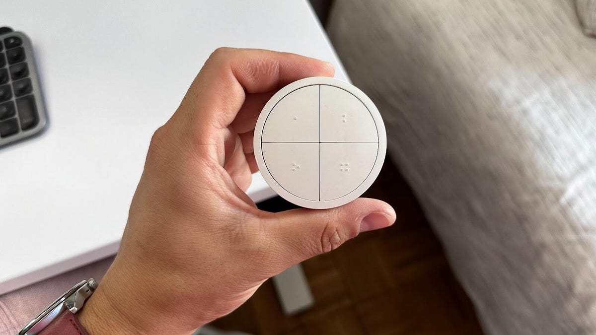 hand holding philips hue tap switch above a desk surface
