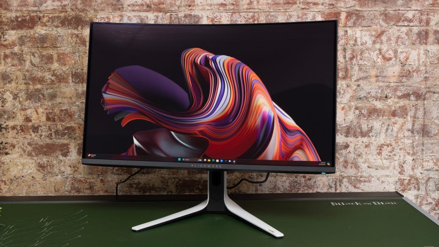 Monitor angled left on a green surface against a brick wall