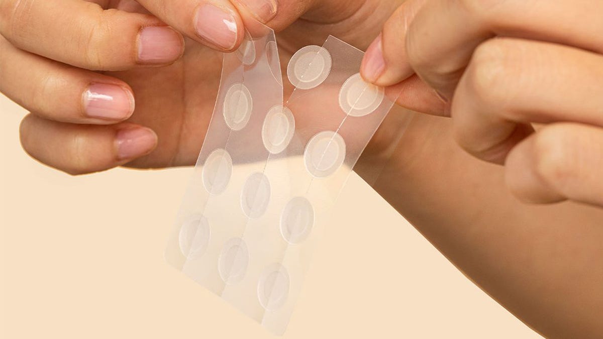 woman squeezes blemish on face