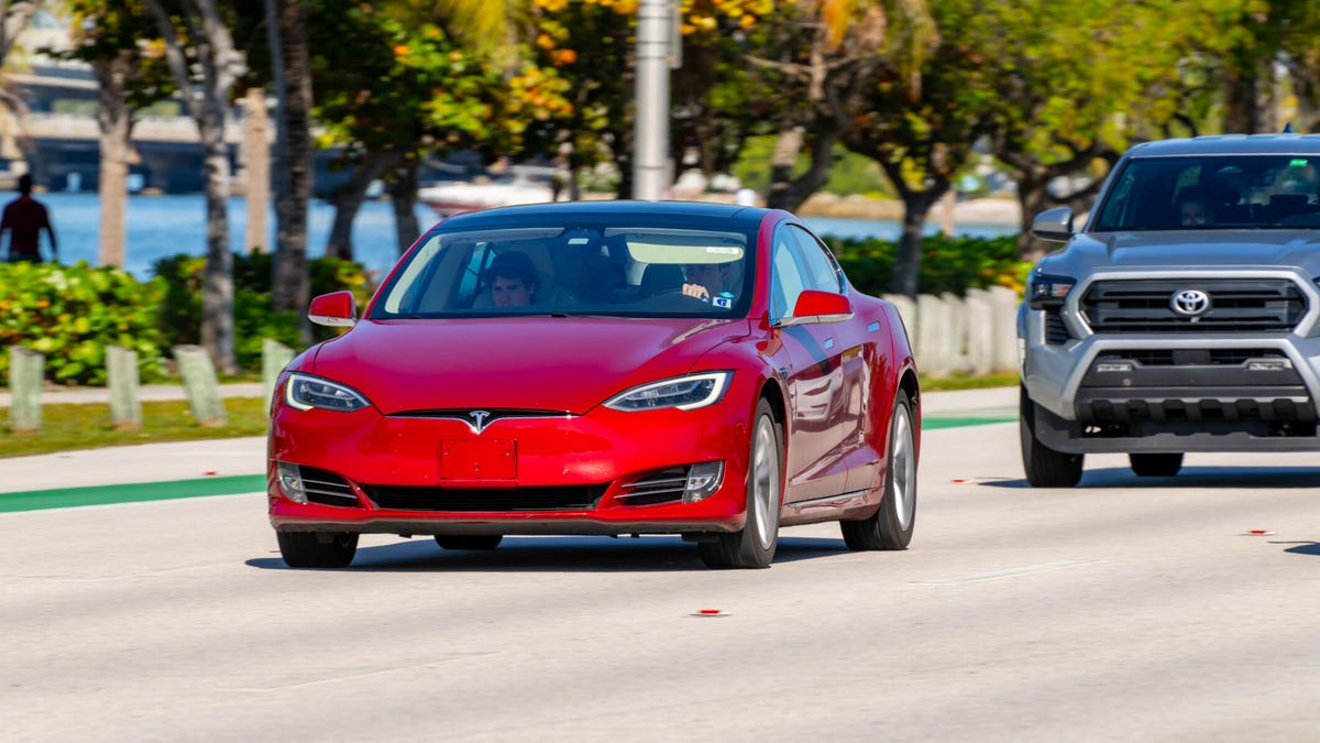 Red Tesla drives in front of car