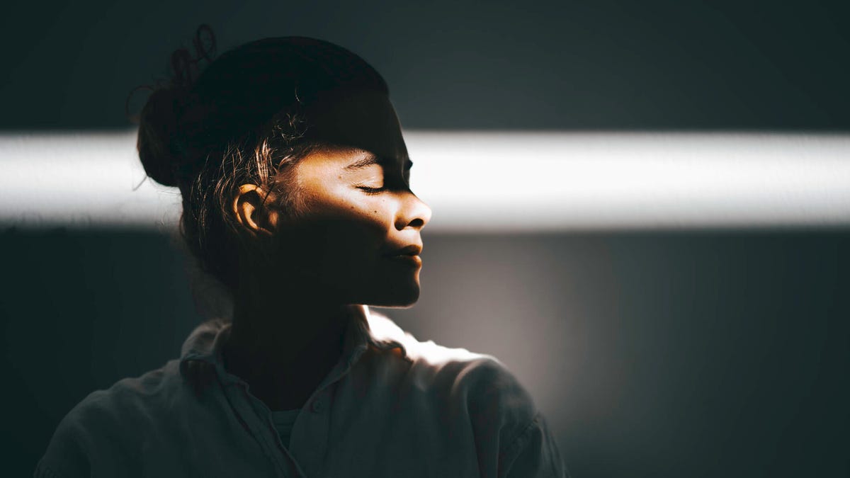 Woman's closed eyes illuminated by a ray of sun