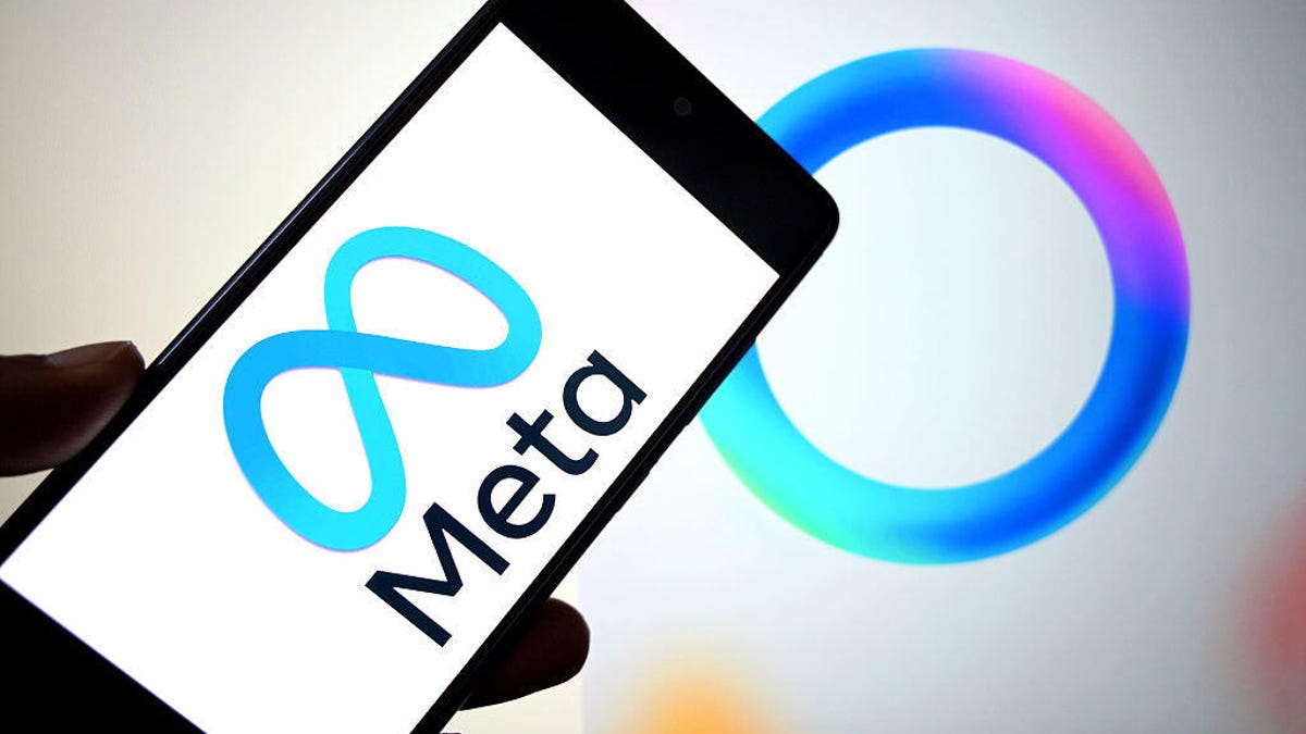 A hand holds a phone with the Meta logo on it.