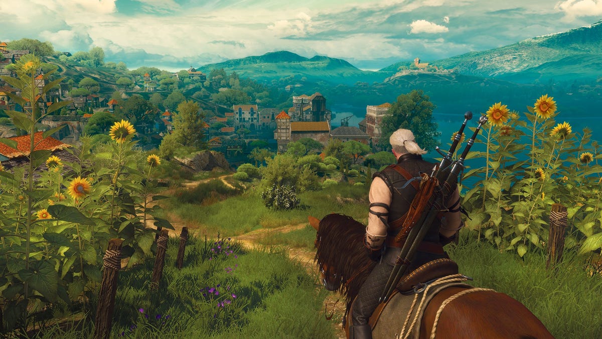 Geralt, sitting on his horse, gazes out over a lush green landscape in The Witcher 3.