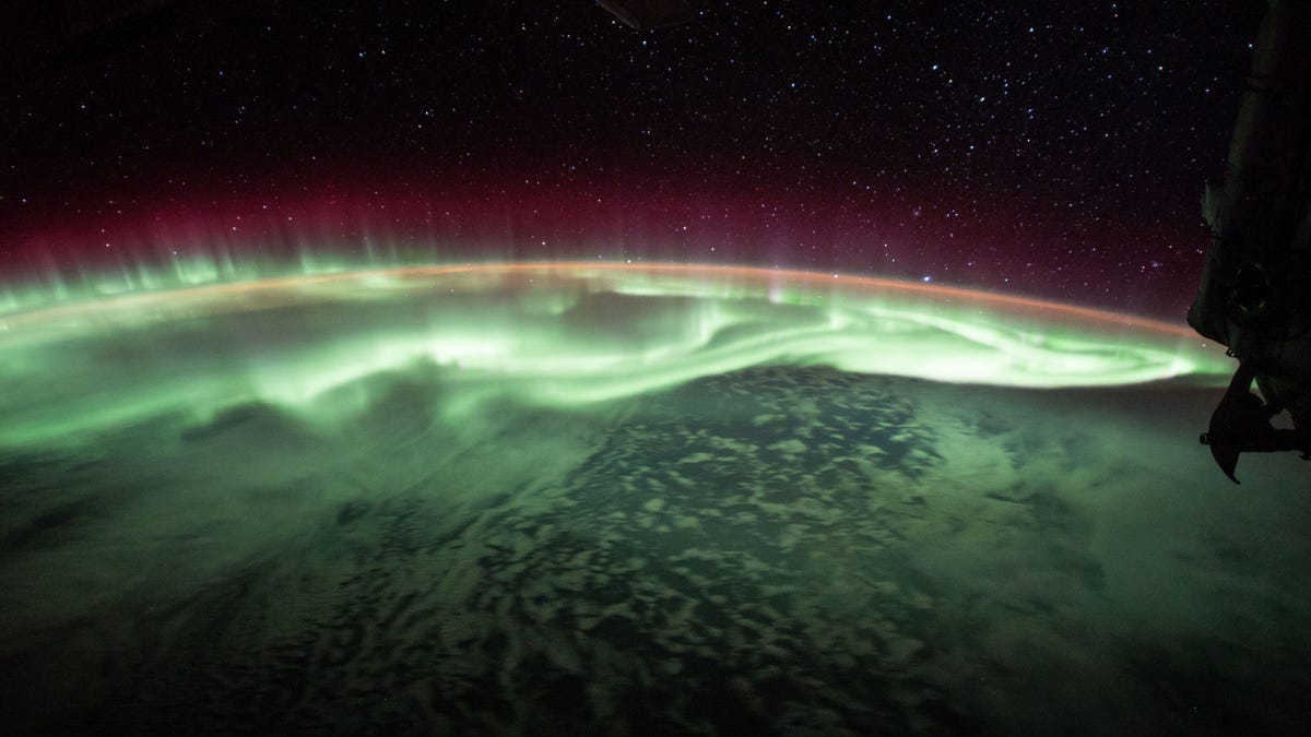 Glowing green aurora like a curtain over Earth as seen from space.