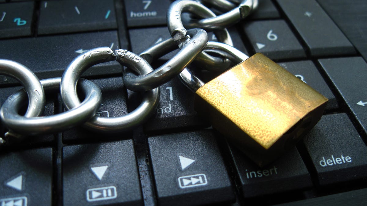 A bronze lock and chain on a black keyboard.