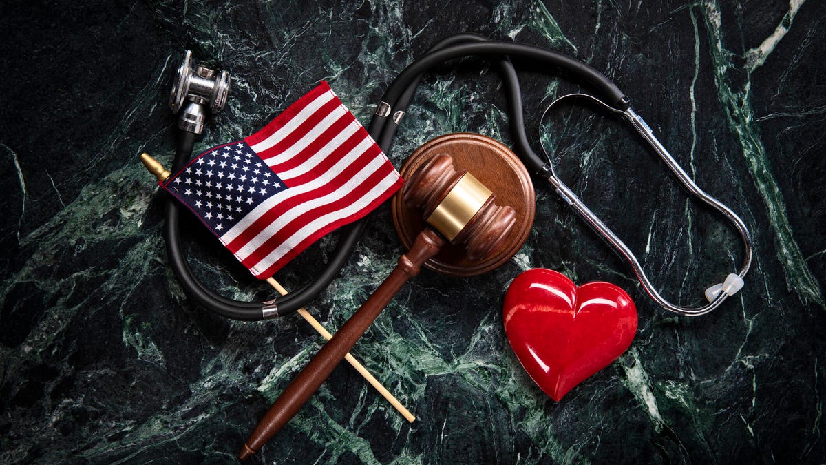An American flag, stethoscope and plastic heart on a marble table