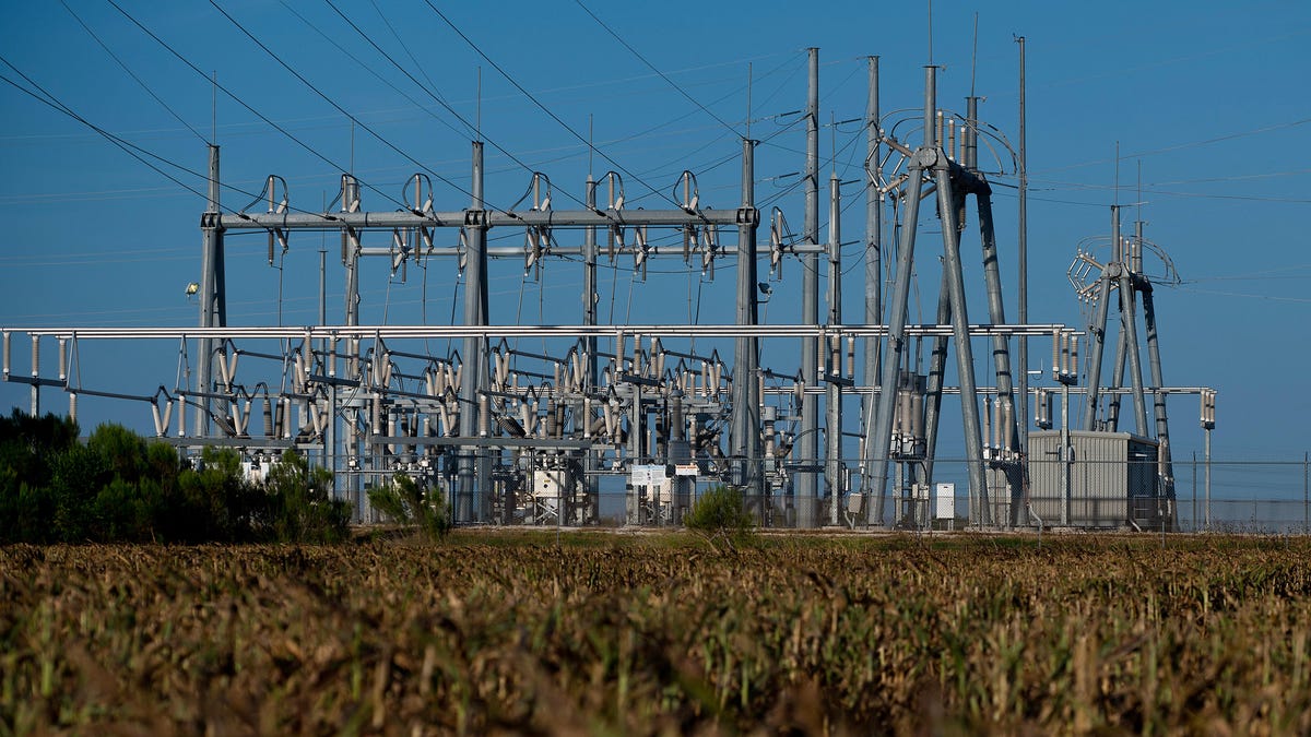 A transmission station behind an field of dry crops.