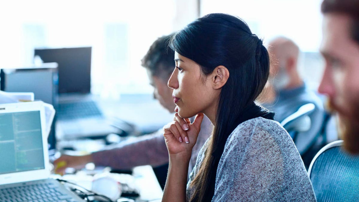 Woman in office, surrounded by men