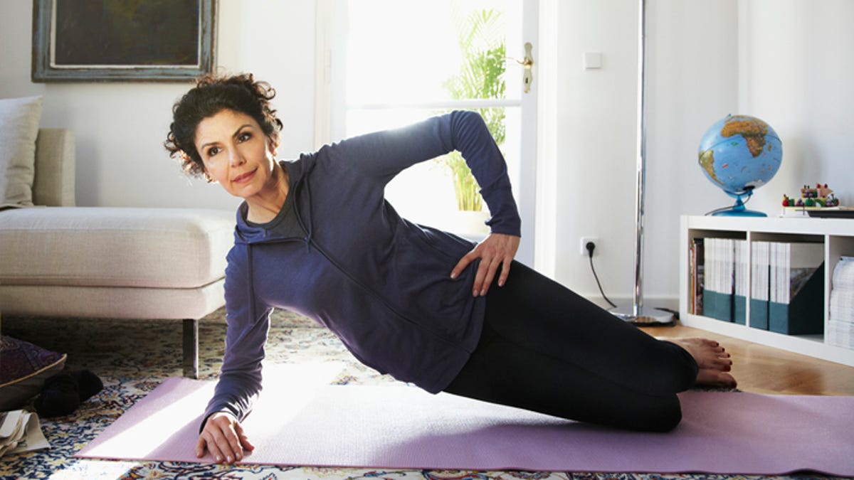 Woman doing yoga on a mat in her living room.