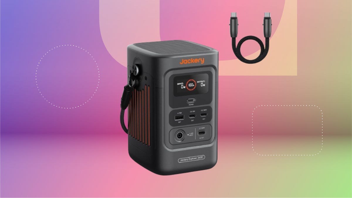 Jackery Explorer portable power station with display screen and multiple ports including USB-C, USB-A, AC and DC -- shown with USB-C cable beside it. Set against a red and purple gradient background.