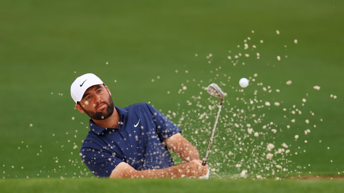 Golfer Scottie Scheffler hits a shot out of a bunker