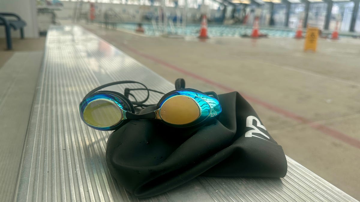 A swim cap and googles sit beside a pool