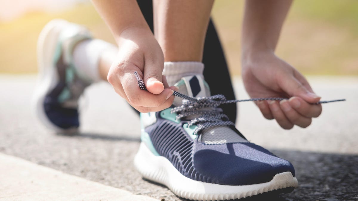 Low Section Of Woman Tying Shoelace On Road