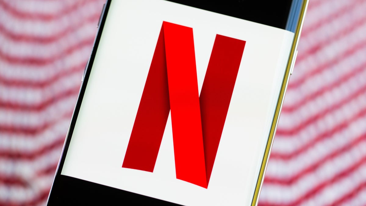 A phone in front of a red and white background displays Netflix's N logo