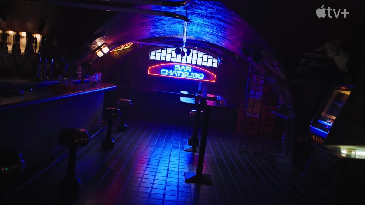 in a still for a teaser trailer for the Apple TV Plus show Neuromancer, a very dark bar is light by a back window and a glowing neon sign that reads BAR CHATSUBO