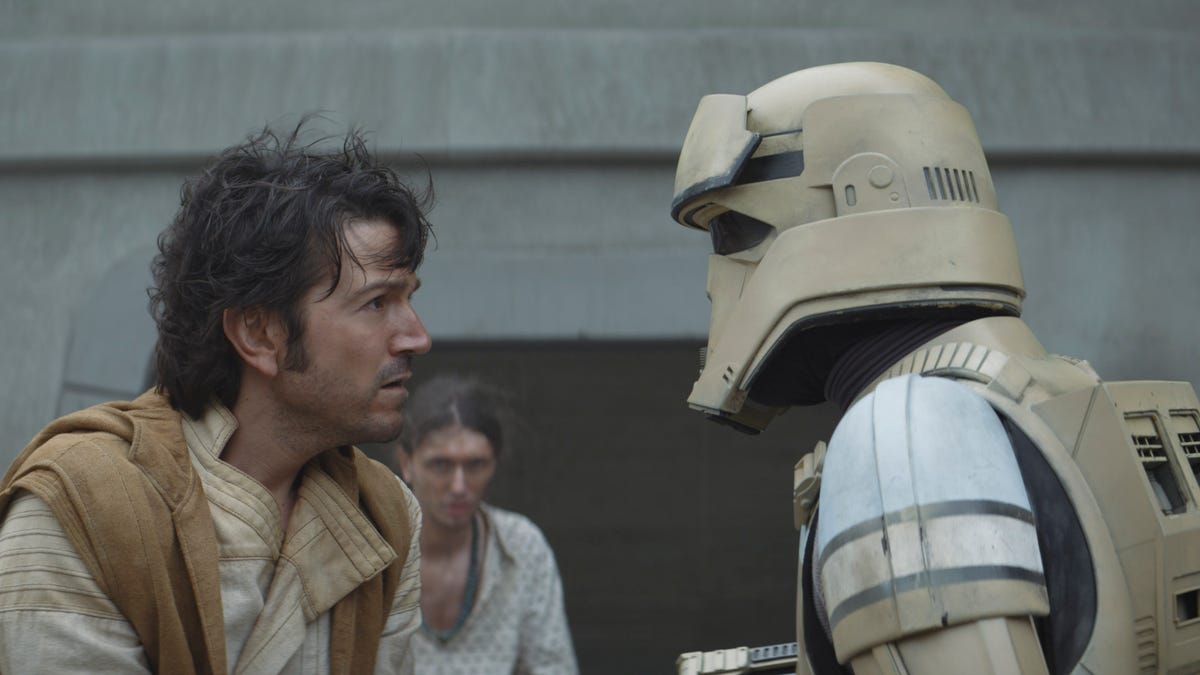 Cassian Andor, his hair blowing slightly in the wind, speaks to a shoretrooper in Andor