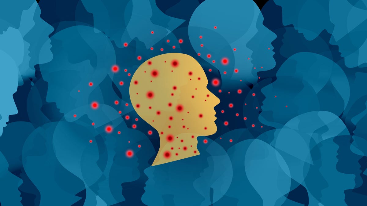 a yellow silhouette of a head is surrounded by spiky red dots, on top of a jumble of blue silhouette heads on a dark background