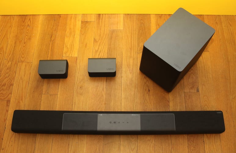 The Vizio M512a-H6 soundbar, subwoofer, and dual rear speakers on a wooden background. 