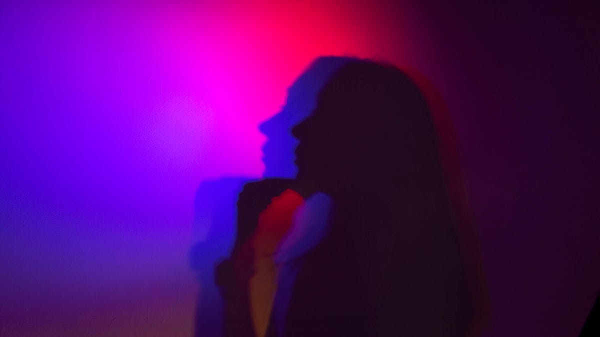 An image of someone's shadow against a neon pink and purple background gettyimages-1492160812