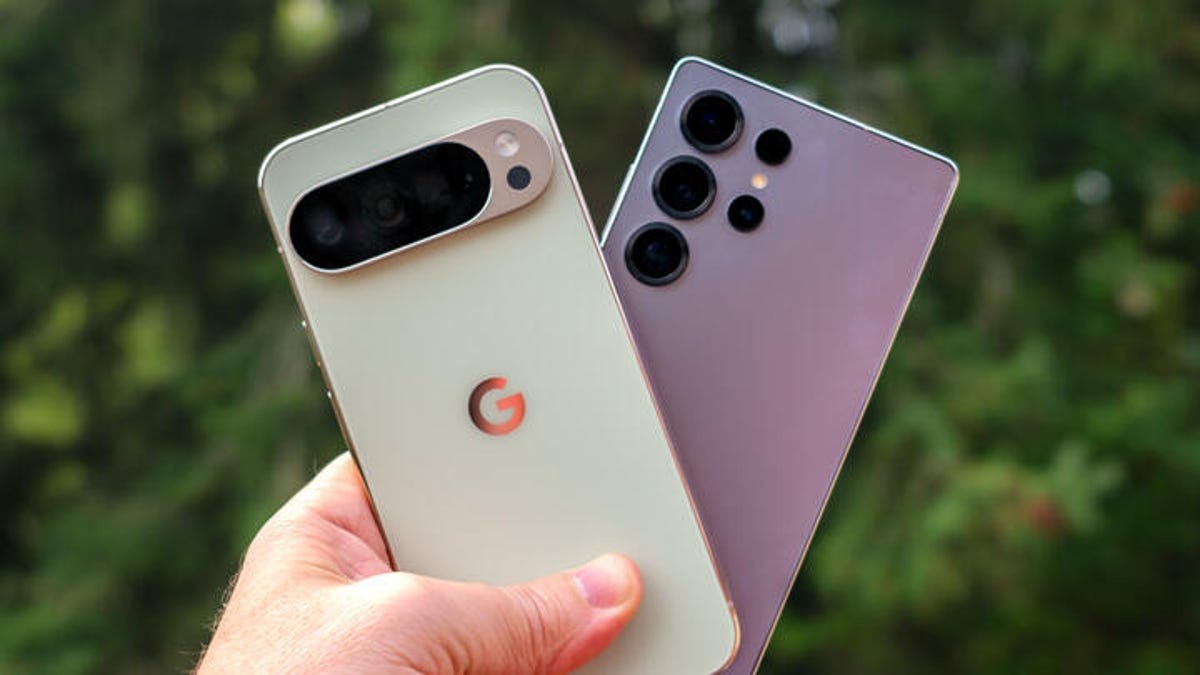 A hand holding a light green Pixel 10 Pro XL phone and a silver Galaxy S25 Ultra phones